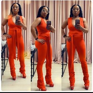 A red tailored jumpsuit with a v-neckline, slouchy leg, and waist belt.